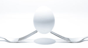 A white egg balanced on 2 forks